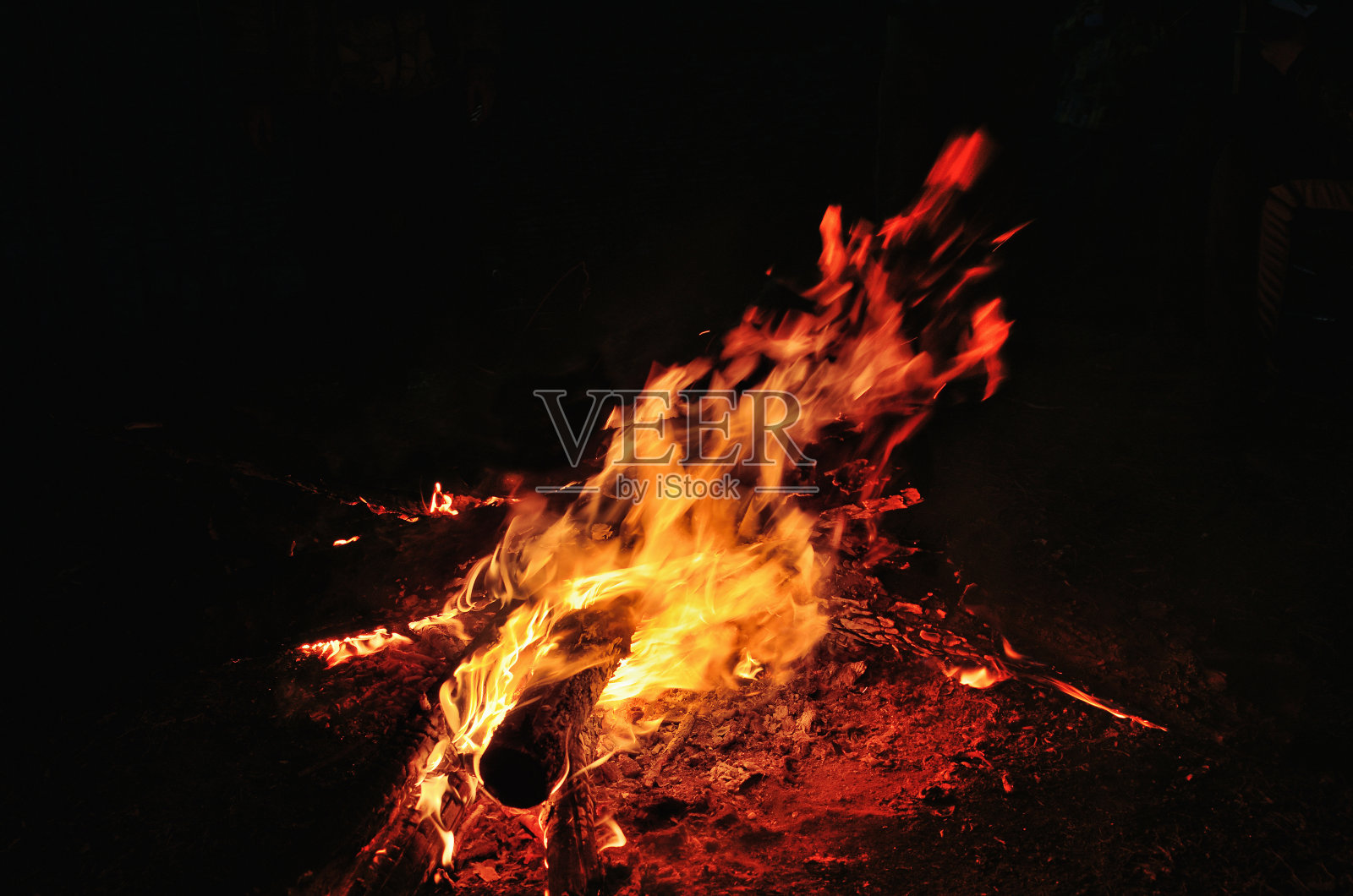 晚上篝火在河边的森林空地上,火星和壁炉。照片摄影图片