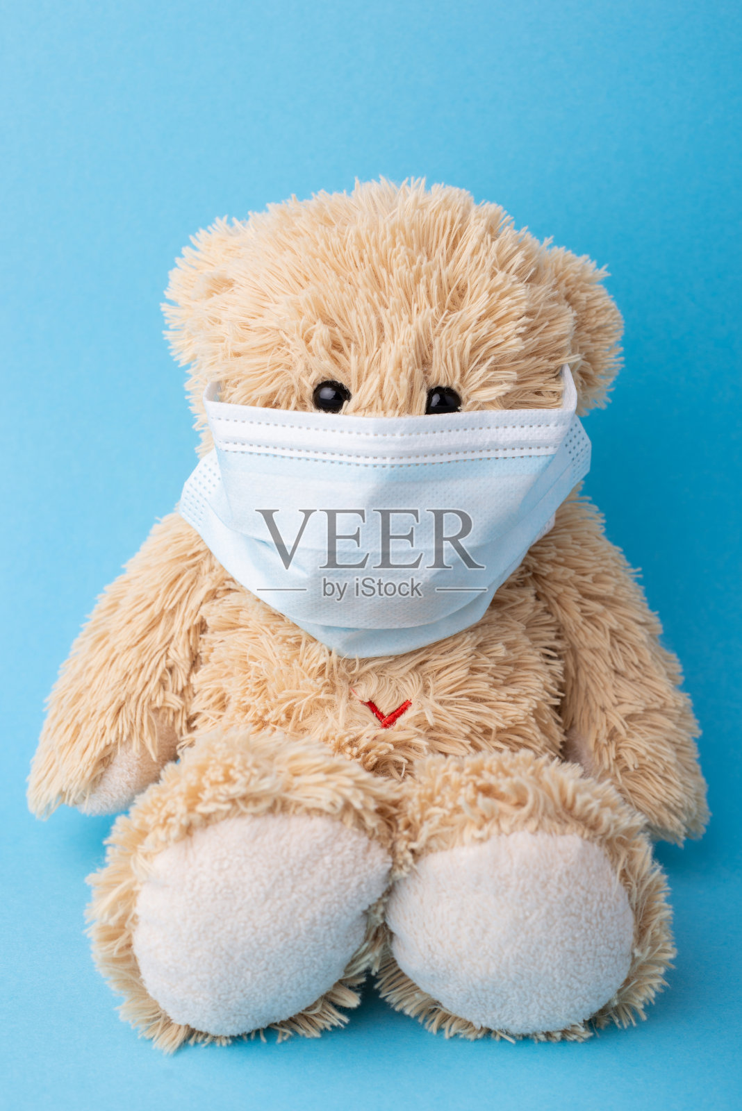 蓝色背景下的医用面具泰迪熊照片摄影图片