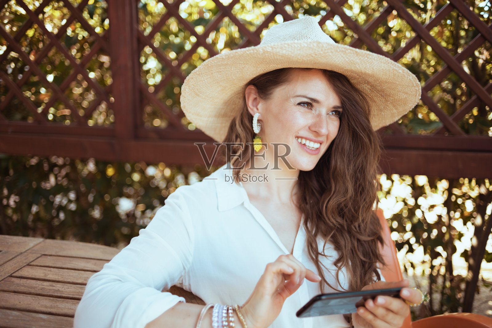 快乐的女人坐在桌边用手机发短信照片摄影图片