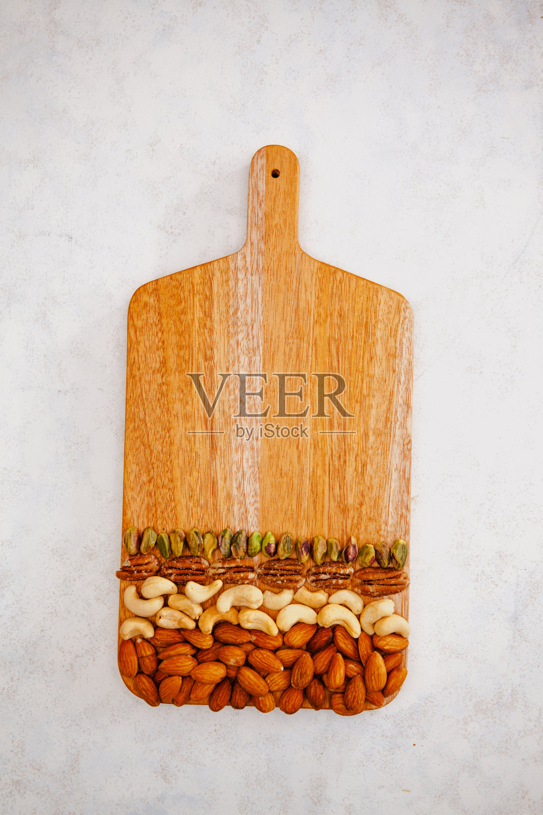 木质砧板上五颜六色排列的各种坚果照片摄影图片