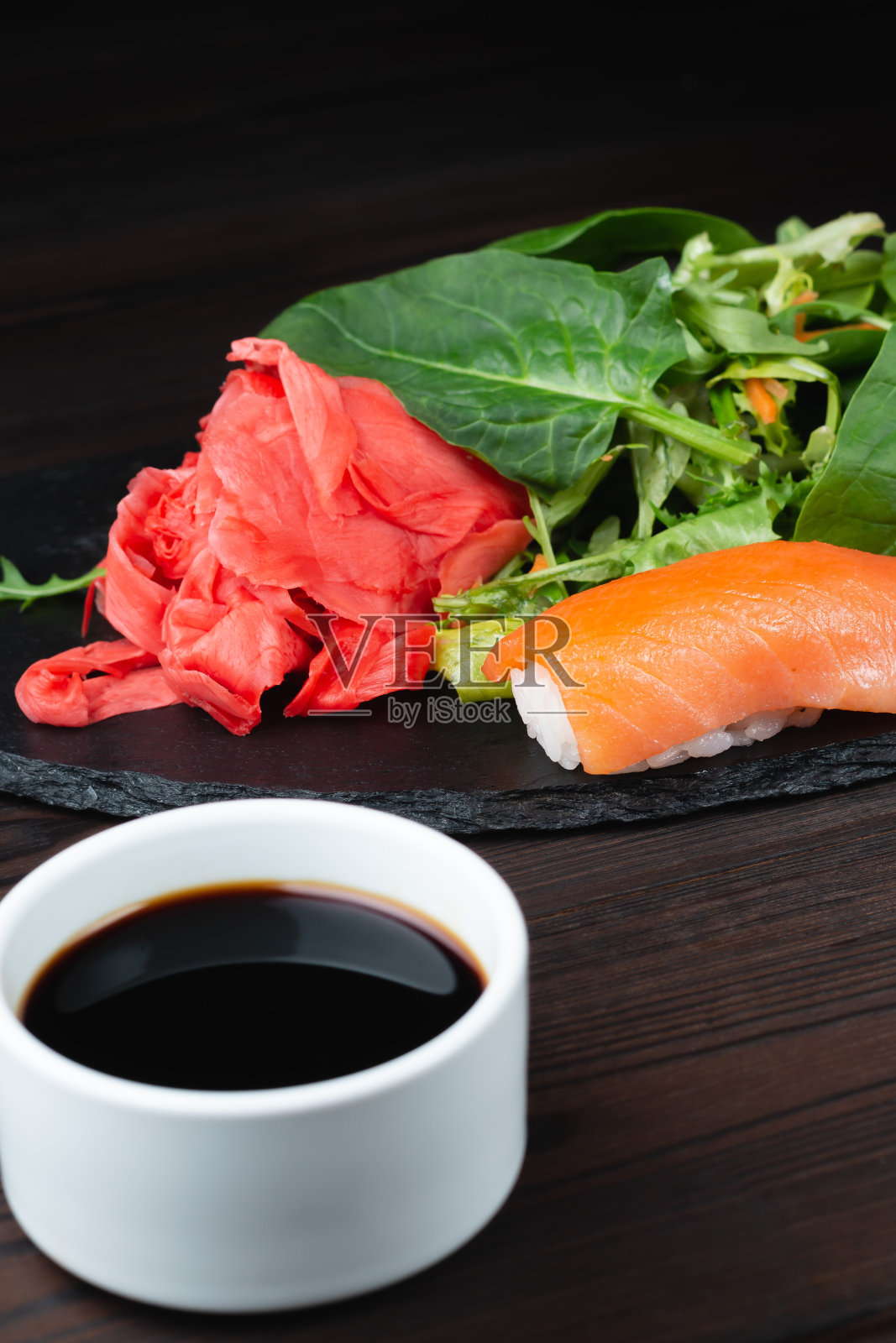 寿司卷配米饭和绿色蔬菜,深色背景上的特写。照片摄影图片