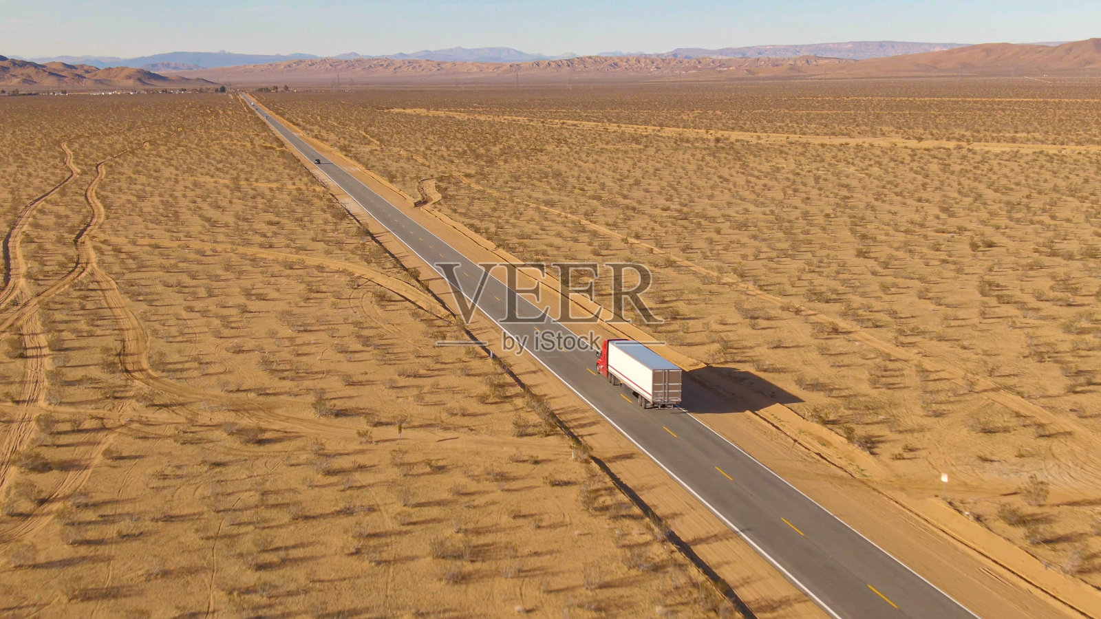 无人机:货运卡车在穿越莫哈韦沙漠的高速公路上行驶。照片摄影图片