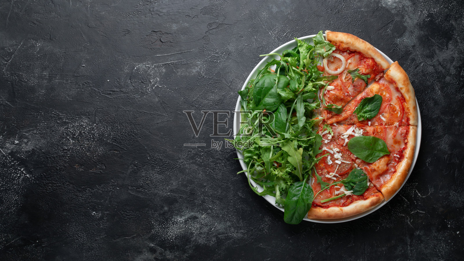 半批萨与绿色在深色石头背景,文字空间照片摄影图片