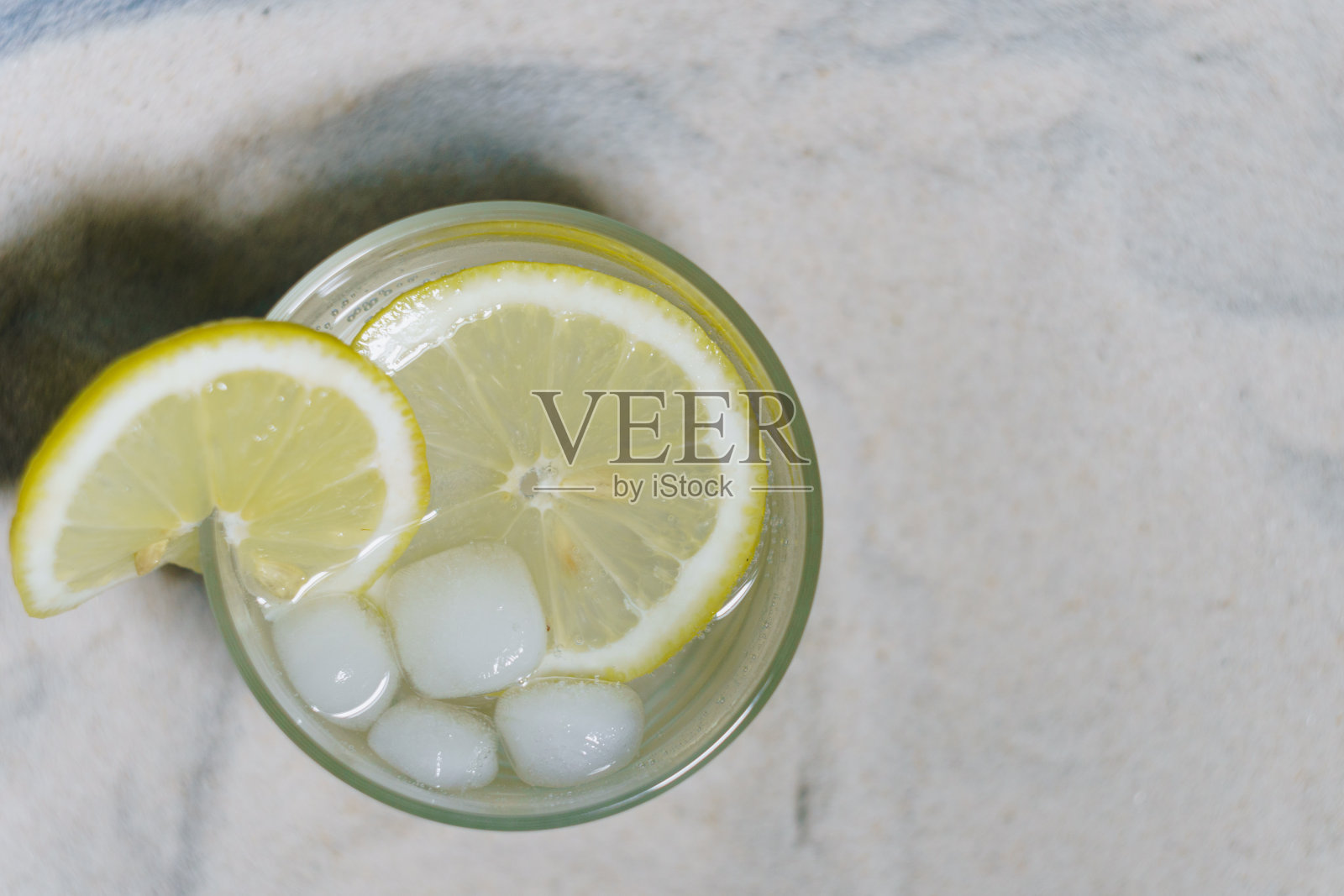 蓝色背景上的沙滩上有冰和波光粼粼的水的透明玻璃照片摄影图片