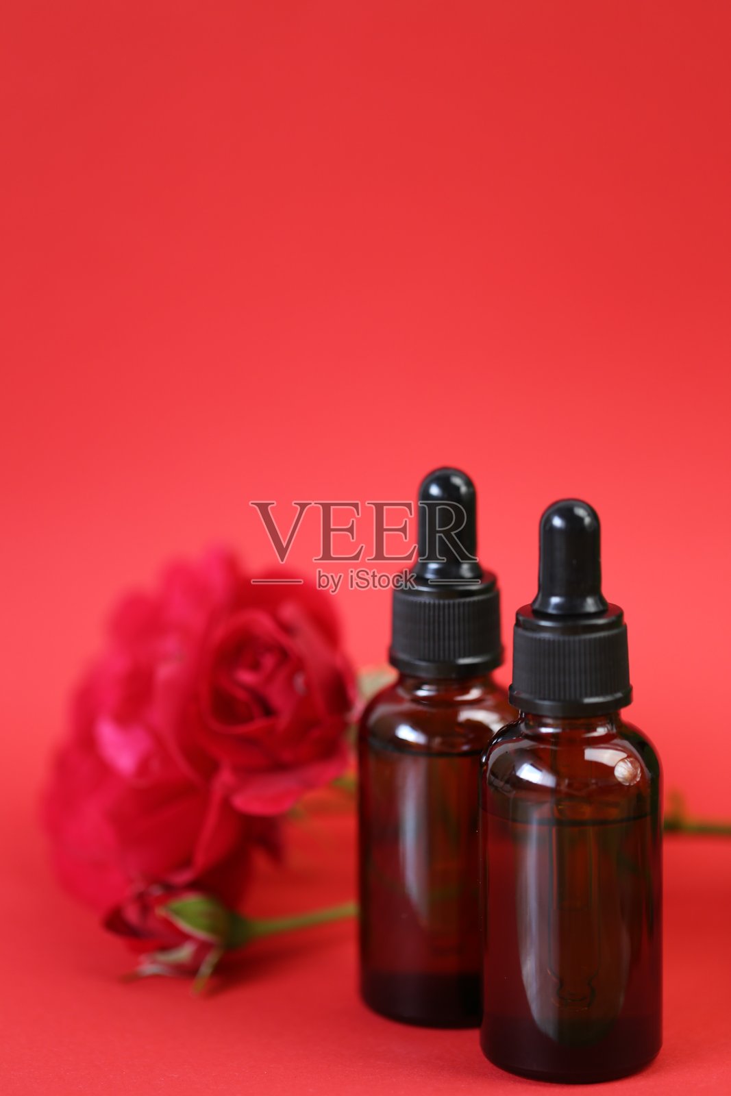 玫瑰提取血清。面对血清。天然有机植物血清。草药天然素食化妆品概念。棕色的玻璃瓶和鲜红的玫瑰花背景照片摄影图片