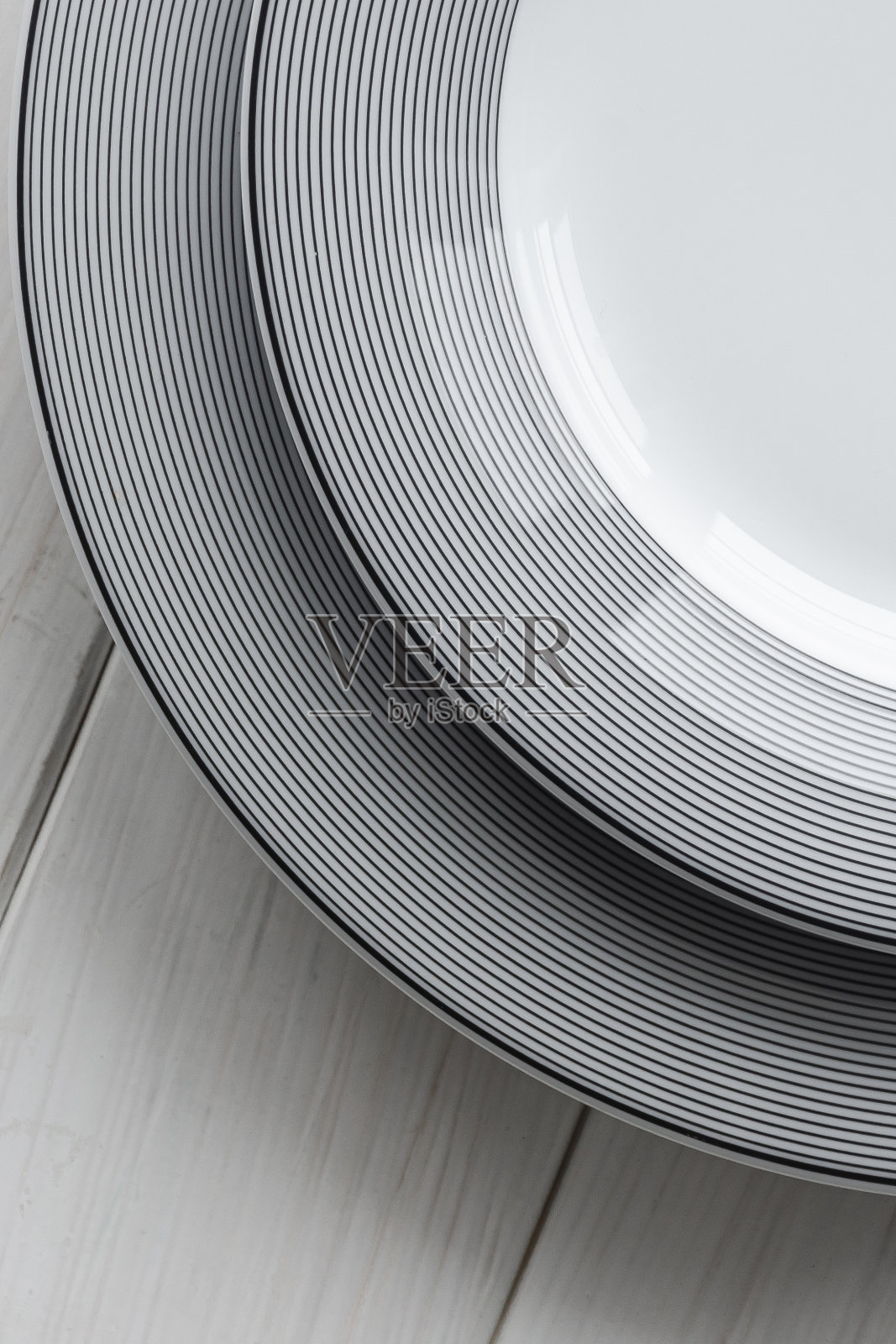 白色桌子上放着白色的灰色花纹的古典圆形瓷盘照片摄影图片