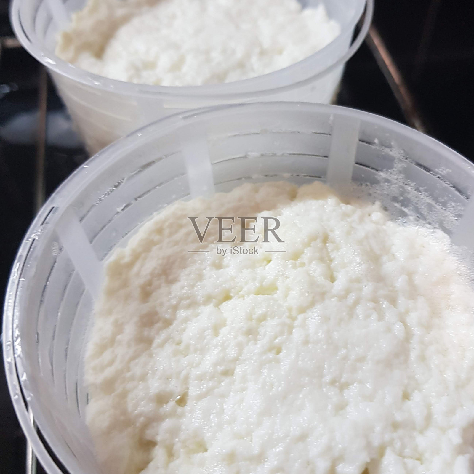 亲手制作意大利乳清干酪。这一过程的分步照片。芝士薄片在芝士模具中沉淀和自压。方料的照片。照片摄影图片