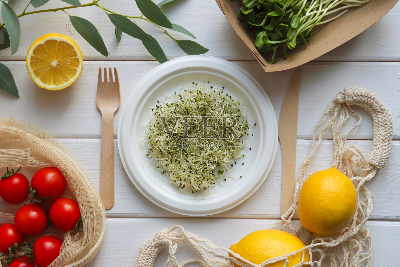 生态一次性有机器皿中的新鲜有机食品。木桌上放着小绿番茄和柠檬。“零浪费”的概念。生态学的概念。俯视图,平放照片摄影图片
