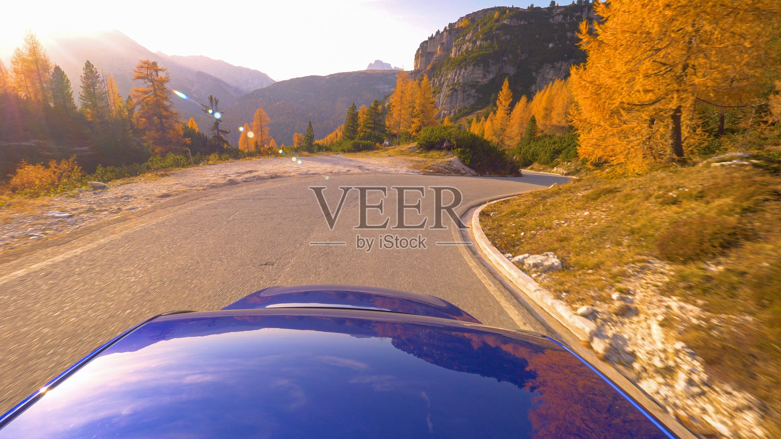 近距离观察:日落时分,一辆蓝色的汽车在Dolomites空旷的风景公路上行驶照片摄影图片