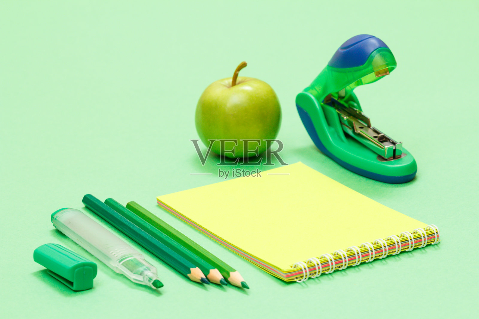 学习用品。彩色铅笔,笔记本,苹果和订书机。照片摄影图片