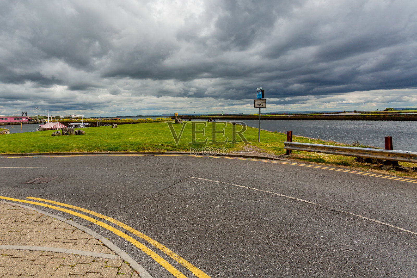 在一条被称为穿越戈尔韦湾的长步道的空旷街道上弯曲,绿色的草地和Corrib河在背景中照片摄影图片