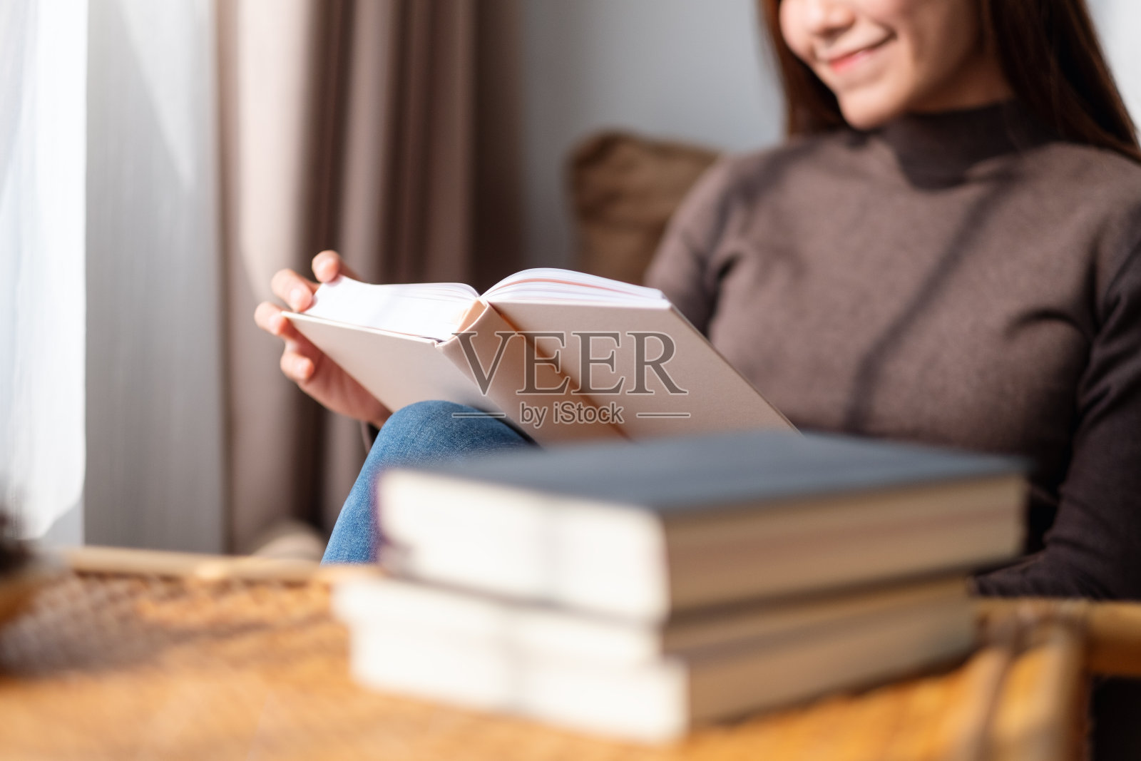 一个年轻美丽的亚洲女人在家里看书照片摄影图片