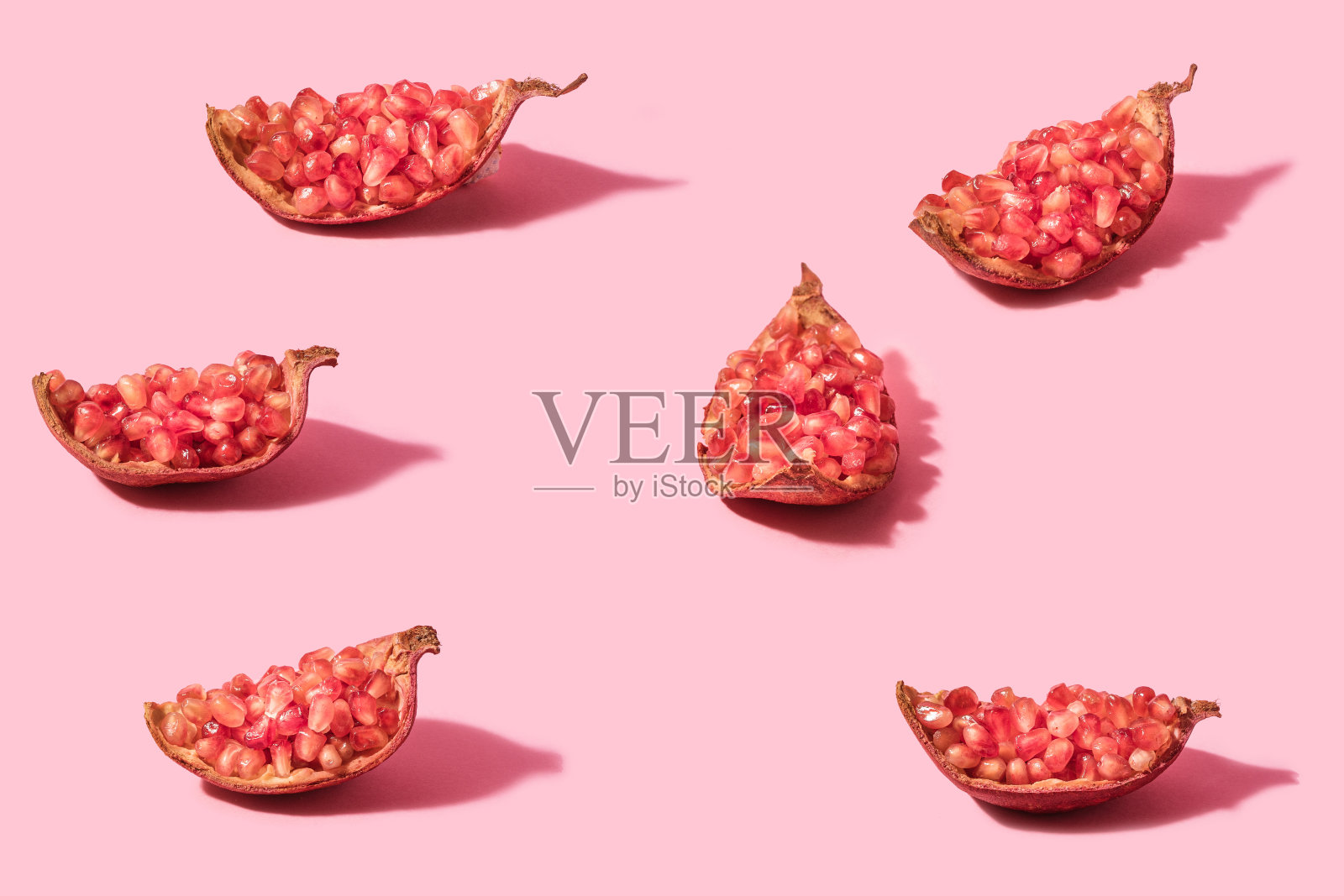 最低限度的概念有机天然六块石榴。用淡粉色作背景。照片摄影图片
