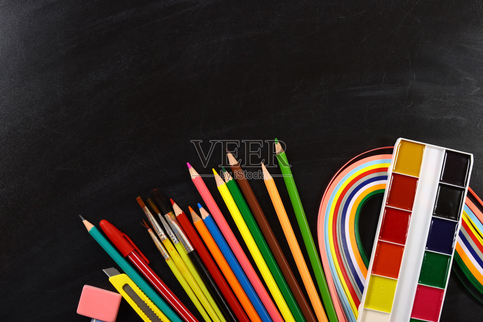 彩色的铅笔、颜料、画笔和文具平铺在黑板上,回到了上学的概念照片摄影图片