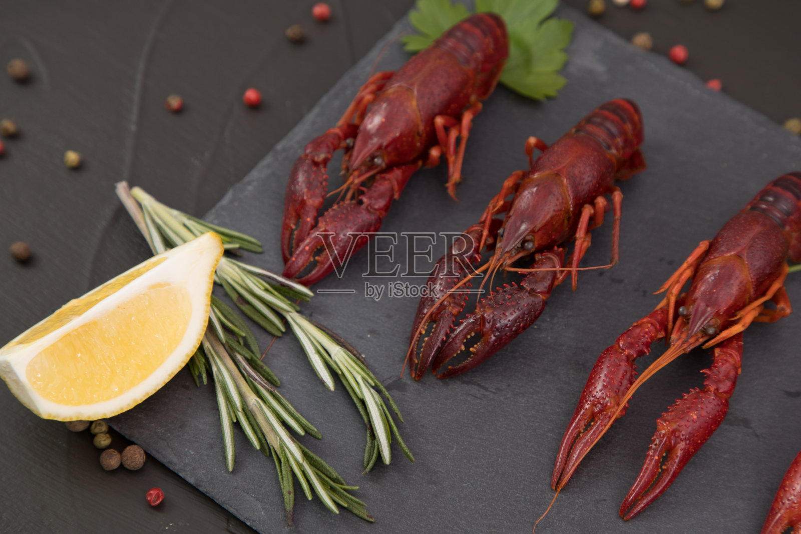 美味的水煮小龙虾特写配上柠檬和欧芹。黑色背景。照片摄影图片