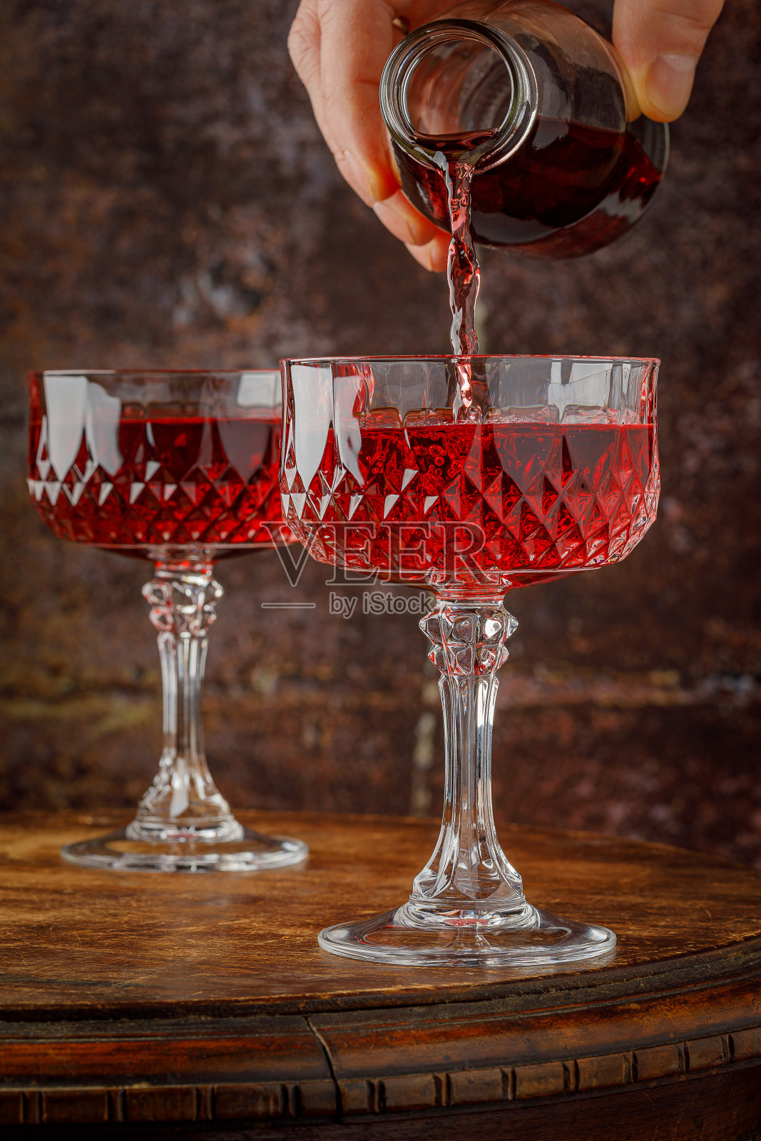 从瓶子里倒出一杯红酒。照片摄影图片