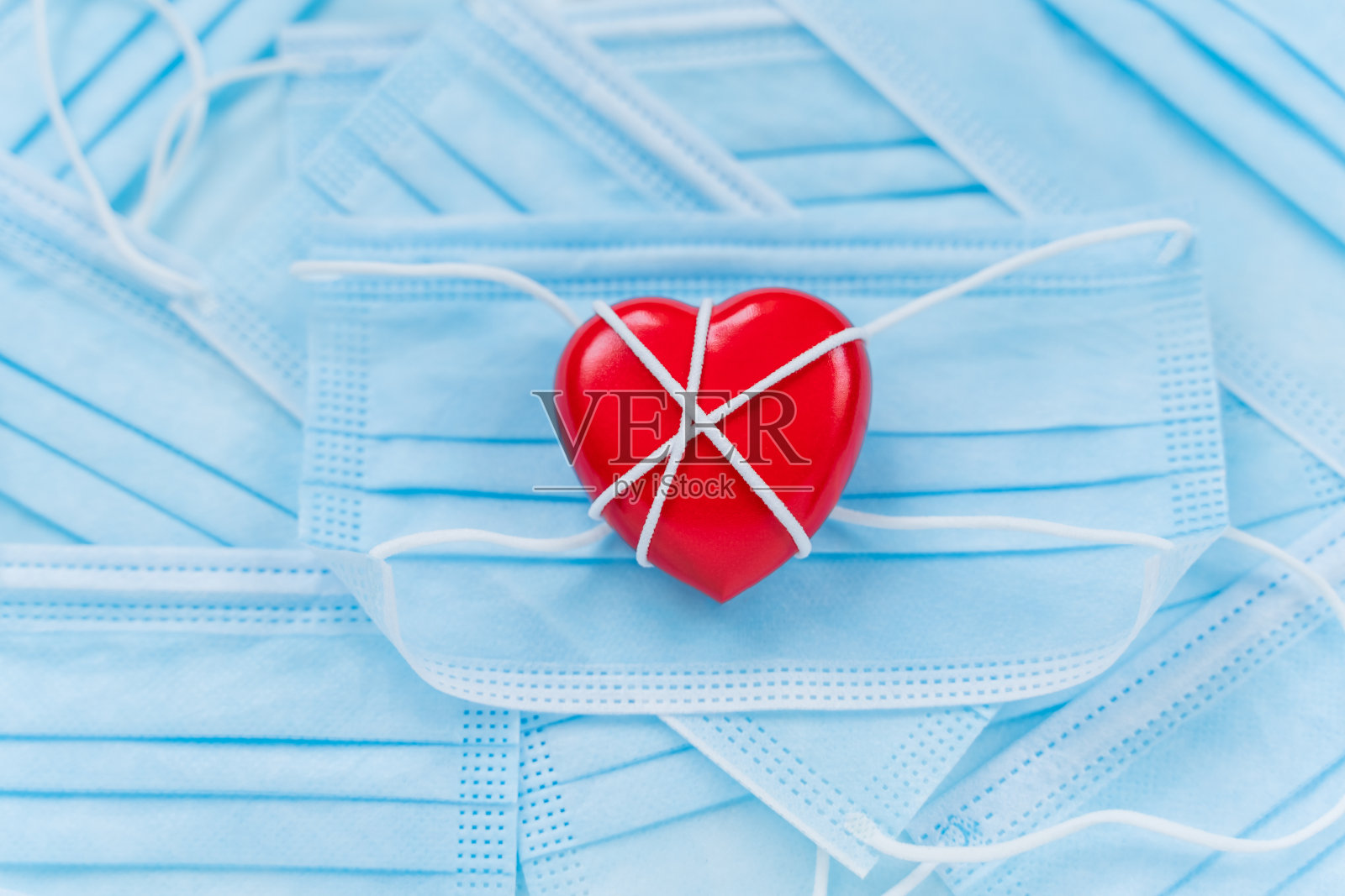 红心躺在一堆防护口罩上。新冠肺炎疫情期间的情侣情人节。概念图。新的现实照片摄影图片