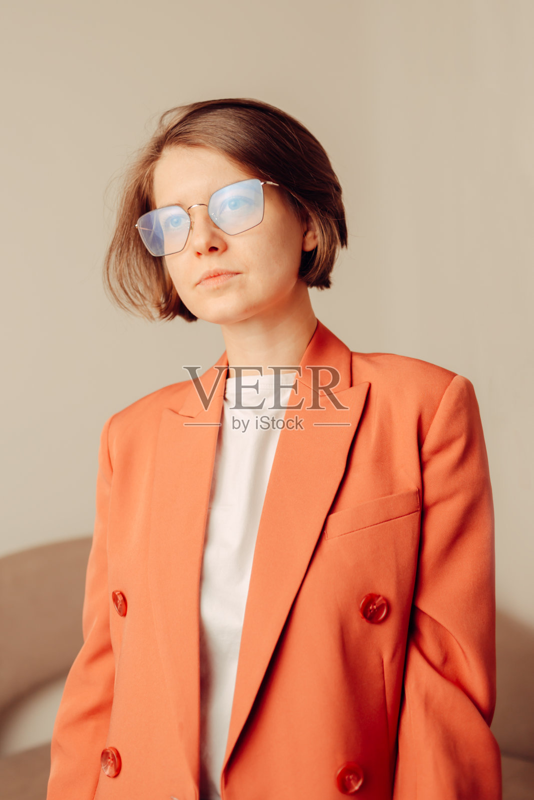 在工作室里快乐的年轻女子在珊瑚夹克的肖像照片摄影图片