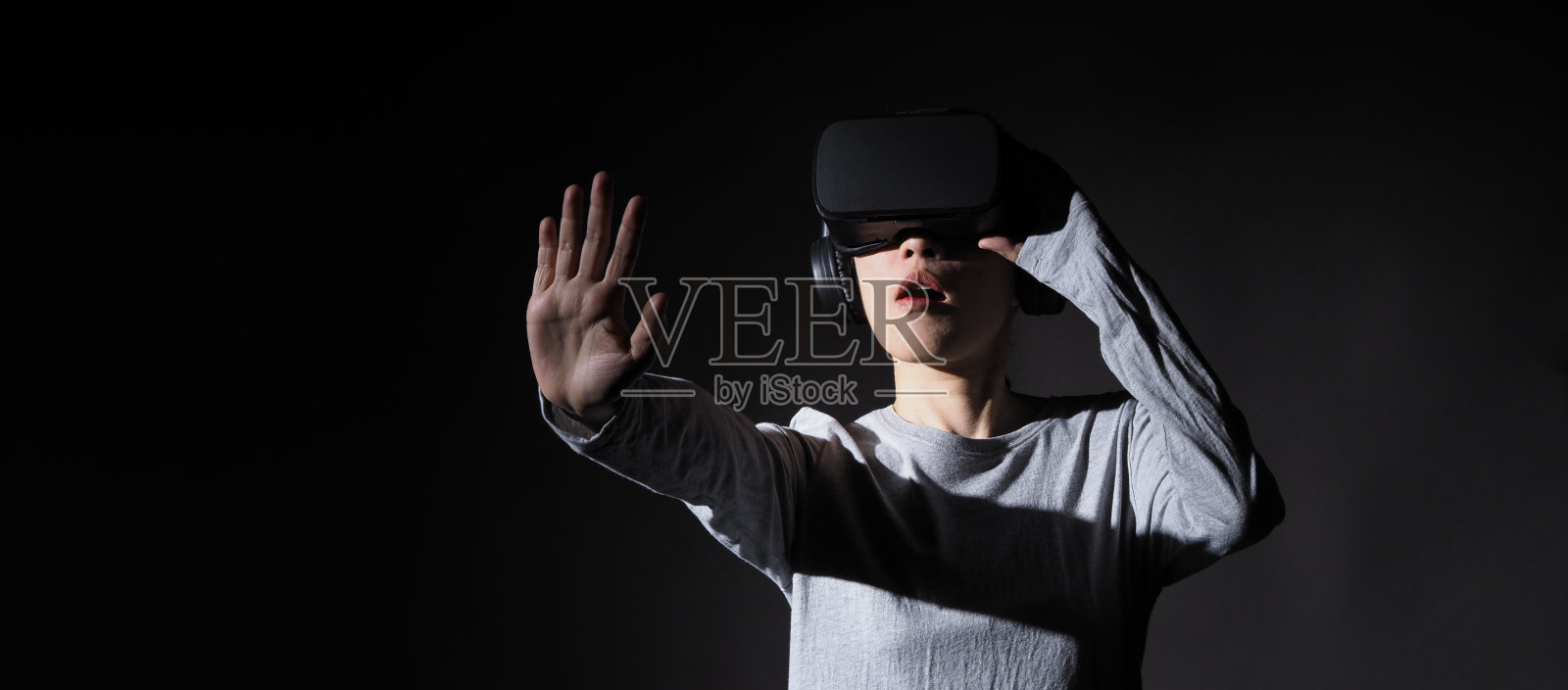 女孩举起双手,戴着虚拟现实头盔。亚洲女人戴着虚拟现实眼镜。未来主义的概念。数字虚拟现实眼镜。女性获得网络体验使用现代黑色虚拟现实。照片摄影图片