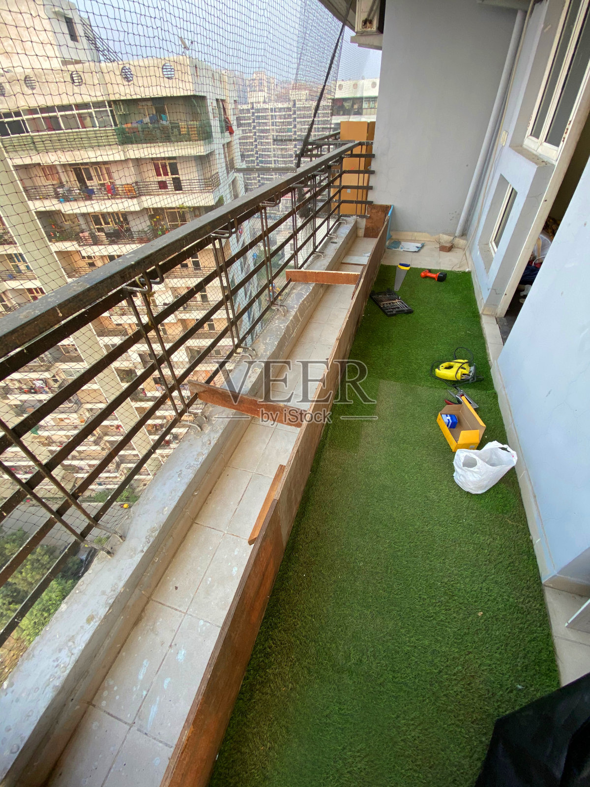 印度Ghaziabad的住宅阳台形象,用人造草皮设计,为盆栽植物建造木制苗床,鸽子防鸟网照片摄影图片