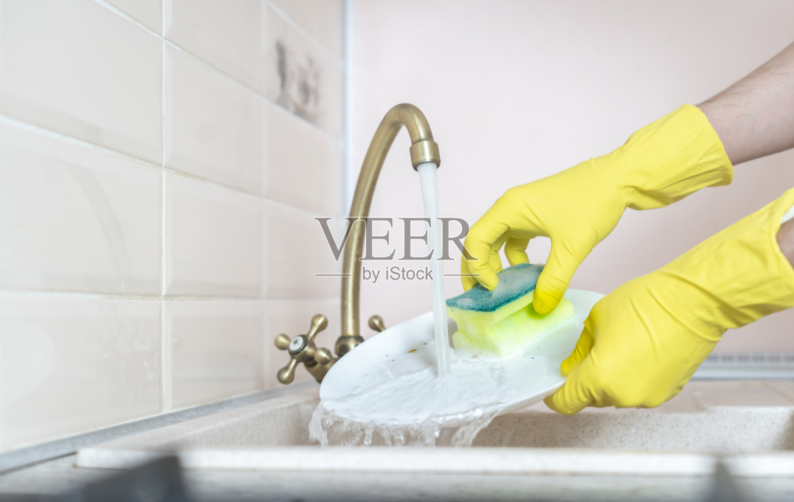 手拿着脏盘子,在厨房水槽里倒水洗它照片摄影图片