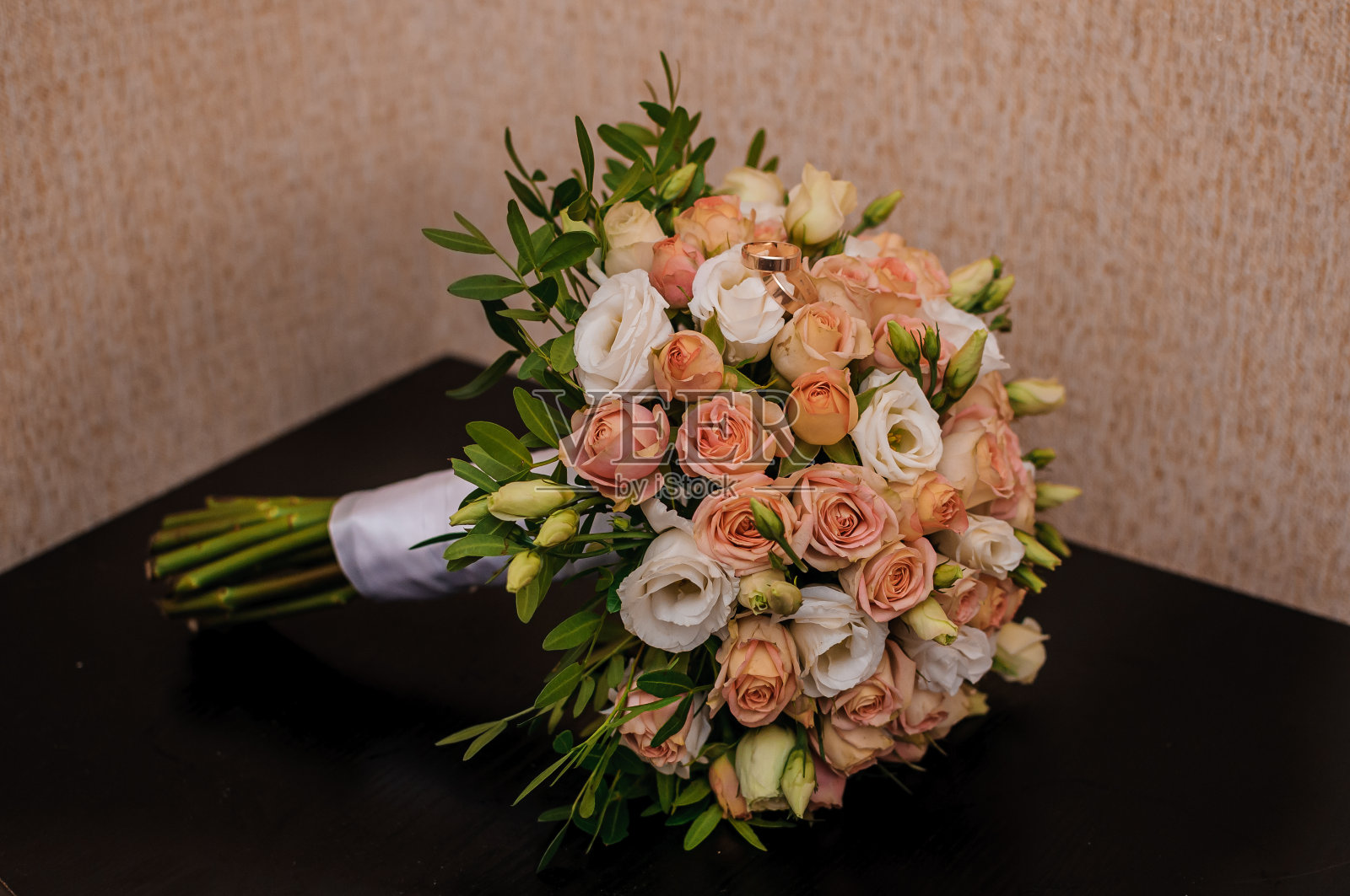 新娘用橙色玫瑰捧花。黄金结婚戒指照片摄影图片