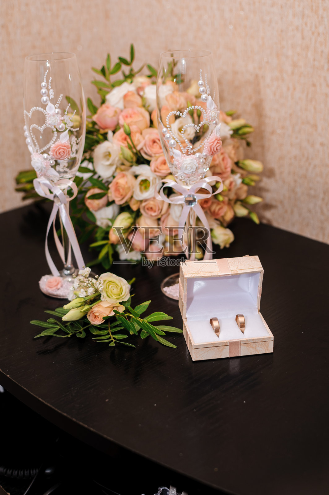 新娘用橙色玫瑰捧花。结婚金戒指。婚礼的眼镜。新郎襟花照片摄影图片