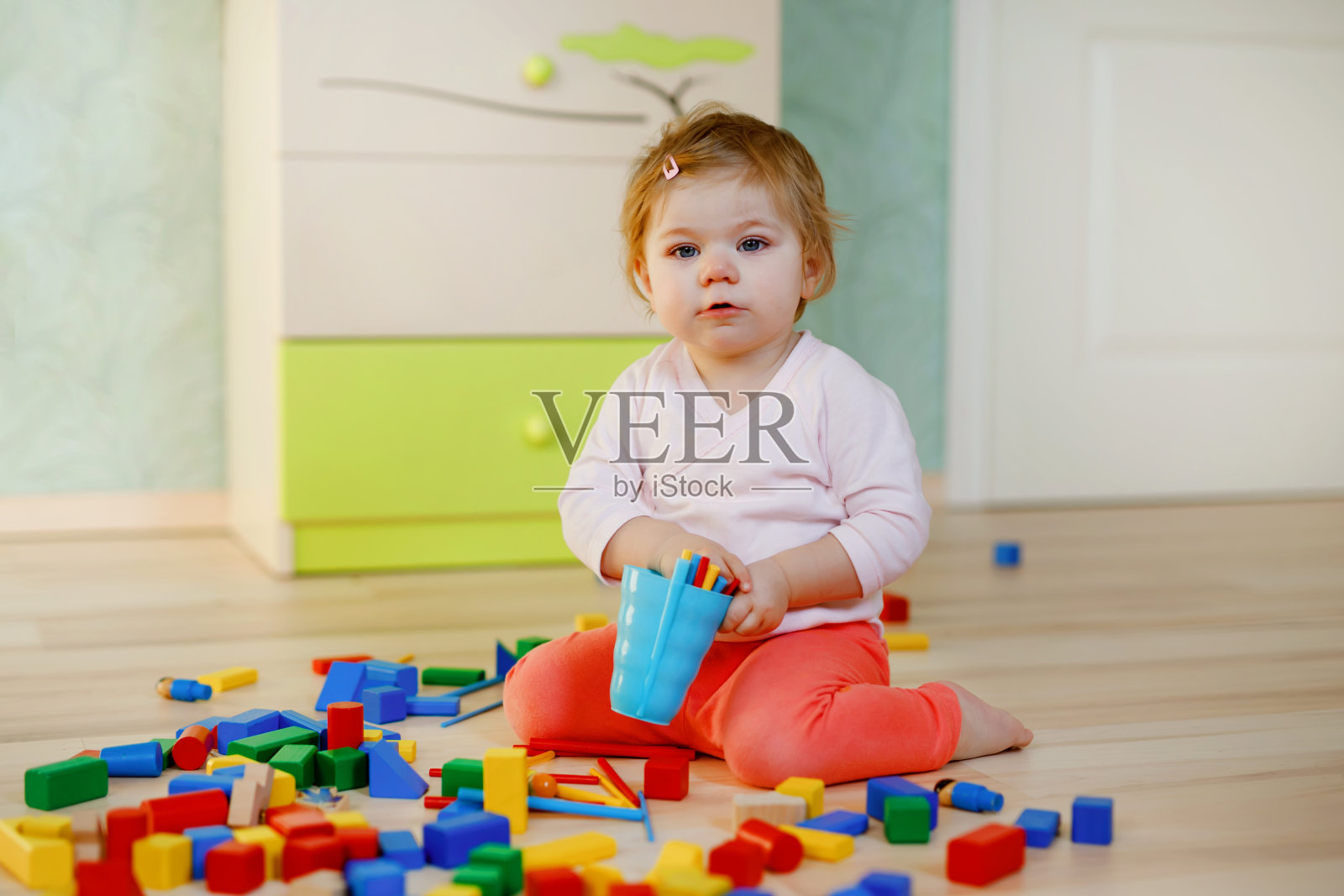 可爱的小女孩在玩益智玩具。快乐健康的孩子在家里或托儿所与五颜六色的不同的积木玩得开心。婴儿在室内爬行和学习颜色和形式照片摄影图片