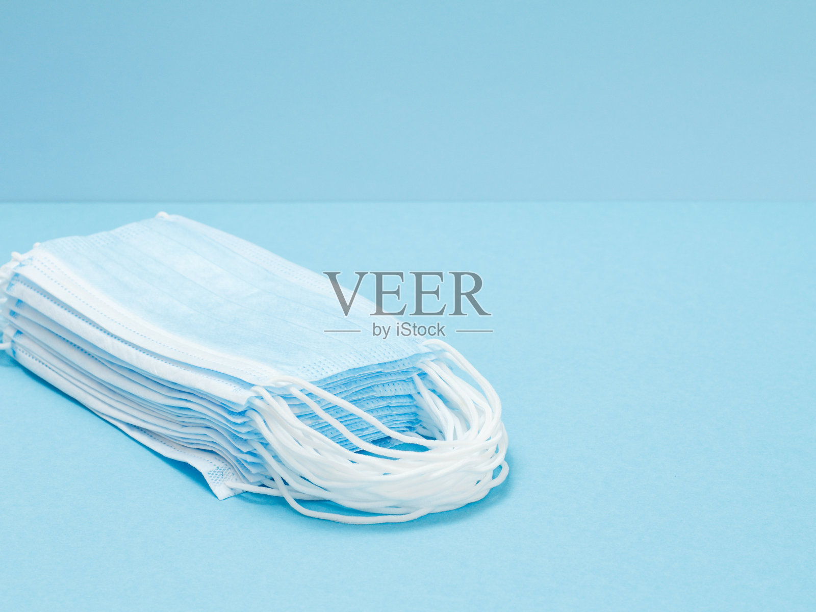 蓝色背景下堆叠的医用口罩。照片摄影图片