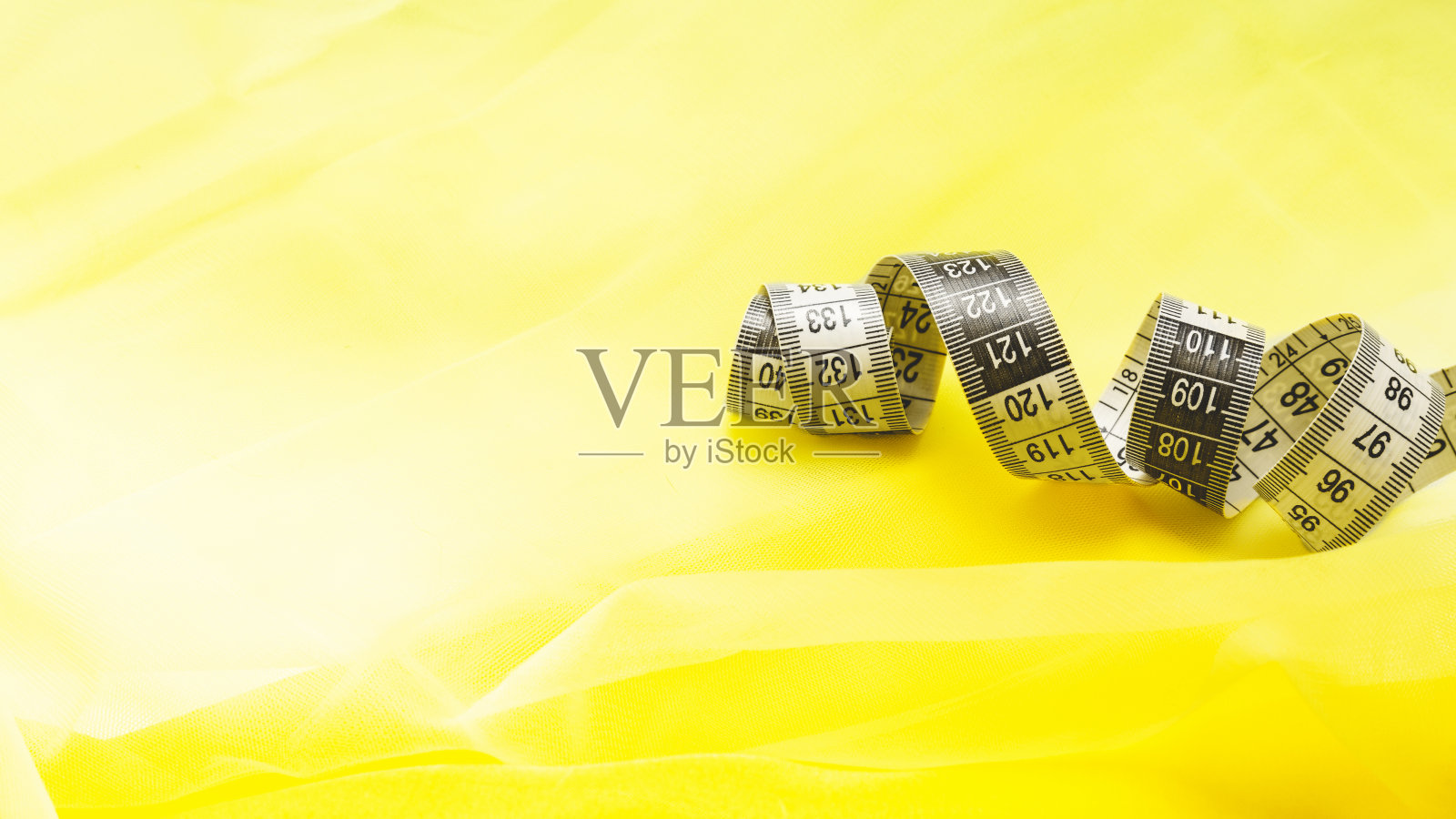 2021年的流行色。灰色厘米胶带上的黄色薄纱织物。副本的空间。近距离照片摄影图片