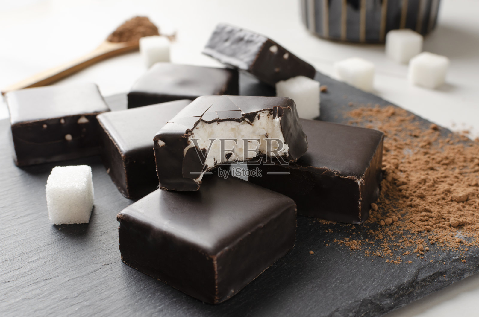 美味的糖果,巧克力和软馅,可可粉和糖在黑色的表面照片摄影图片