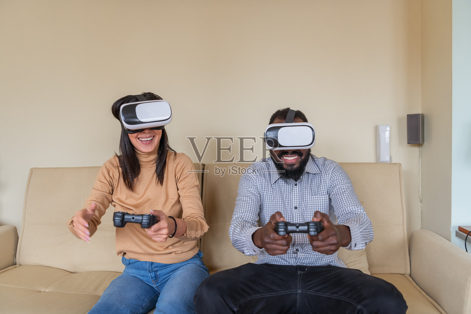 一个快乐的年轻女人正在客厅里用VR系统和她的男朋友玩电脑游戏。照片摄影图片