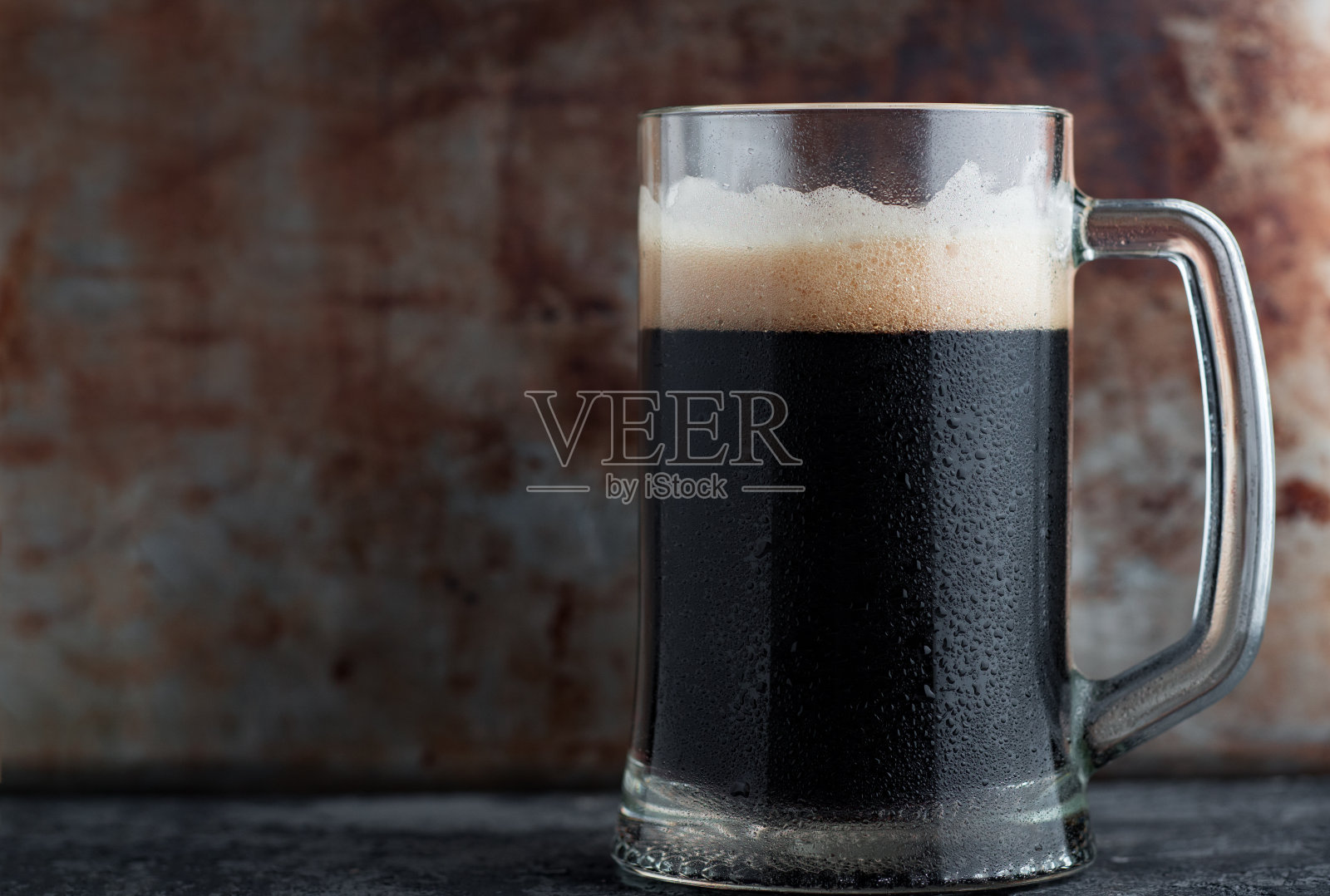 铁质背景上放着一大杯黑啤酒照片摄影图片