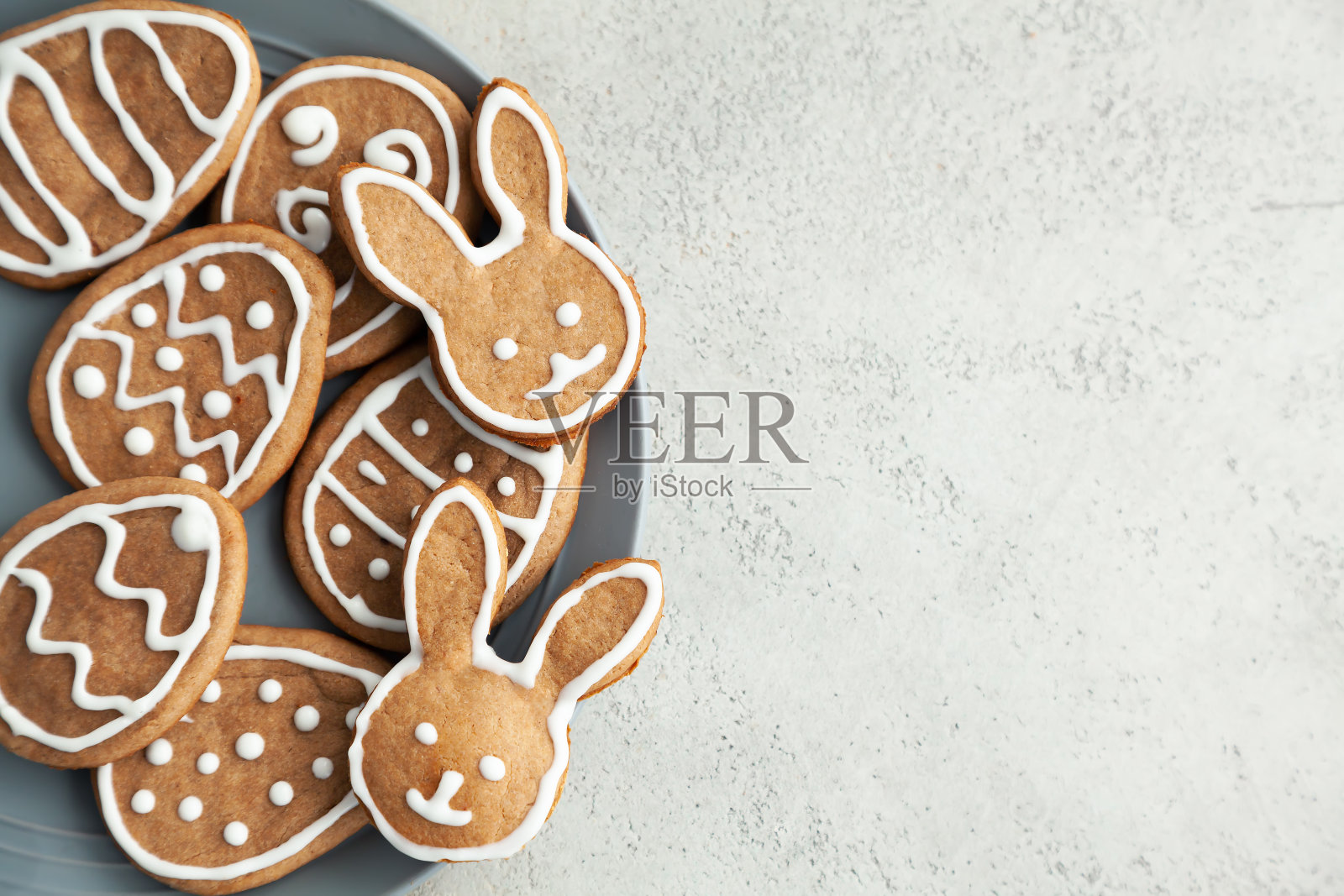 石头背景的灰色盘子上放着复活节饼干。复活节兔子。复制空间和俯视图。照片摄影图片