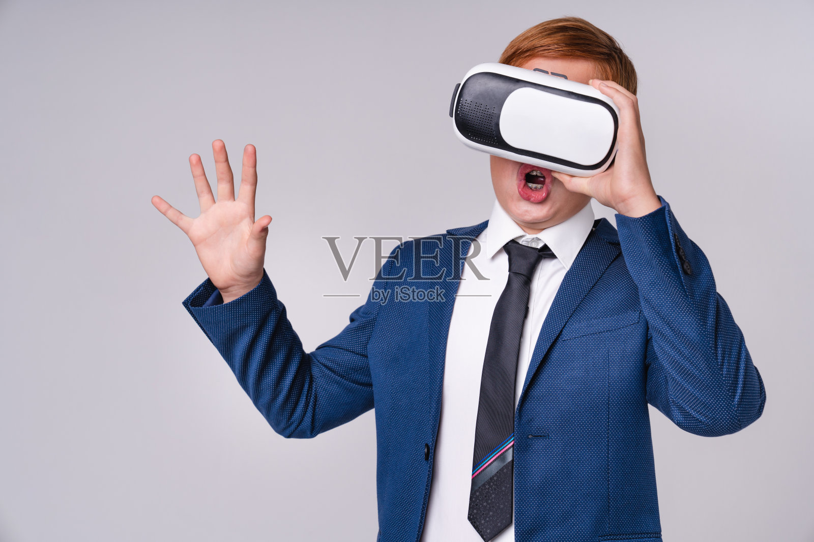 印象深刻的年轻男孩在正式服装使用vr眼镜孤立的灰色背景照片摄影图片
