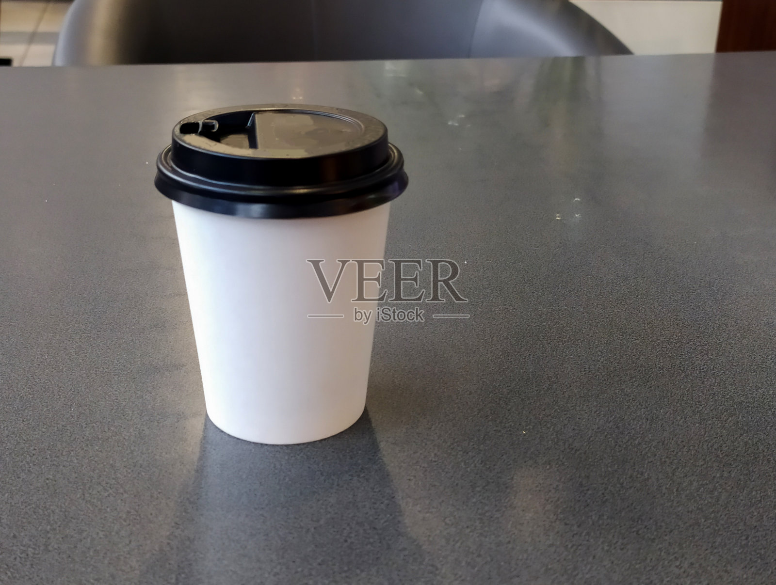 黑色的桌子上放着一个白色塑料杯和一个棕色的盖子。快餐的概念。照片摄影图片
