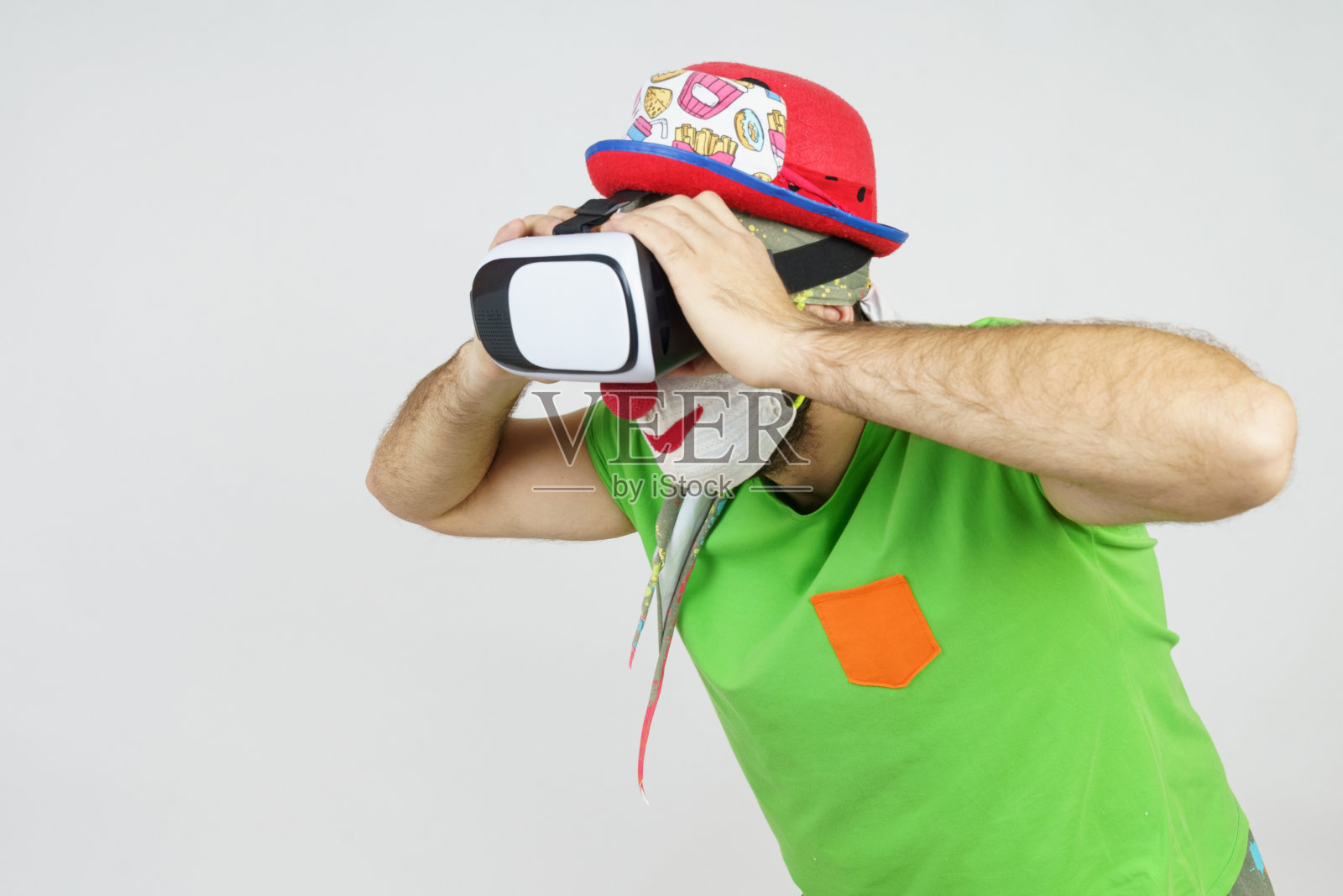 小丑正在玩,他的头上戴着虚拟眼镜,看起来像通过双筒望远镜。孤立在白色照片摄影图片