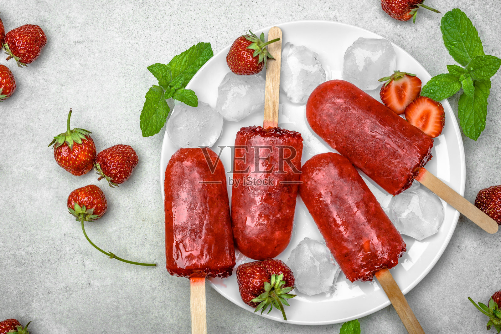 鲜果冰棒配红草莓,冰冻冰沙。多汁的自制水果冰淇淋,清爽的食品理念。照片摄影图片