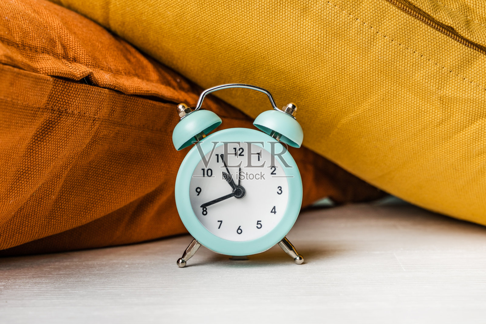 闹钟在彩色枕头的旁边。起床和睡觉的概念照片摄影图片