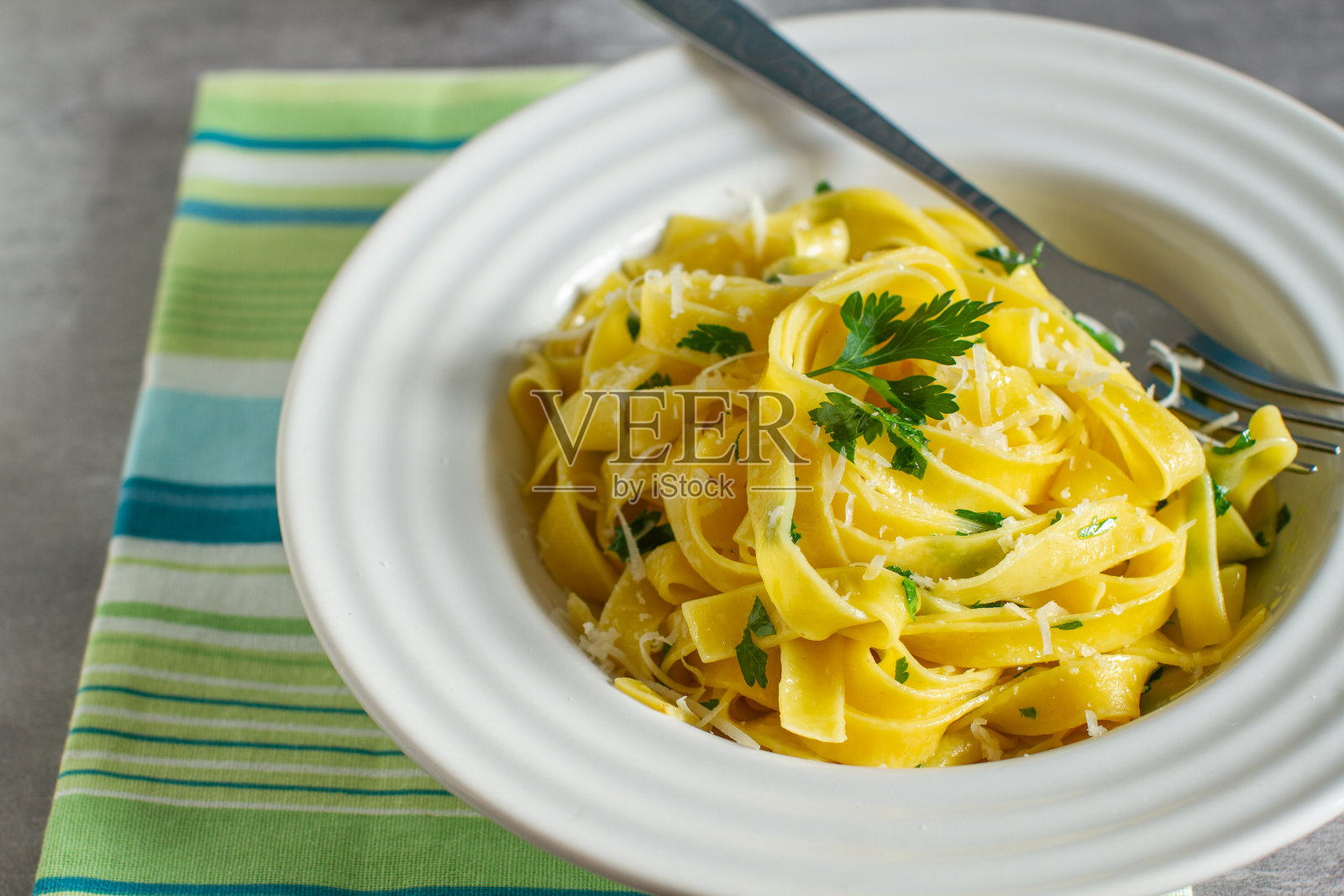 加橄榄油、欧芹和帕尔玛干酪的意大利宽面照片摄影图片