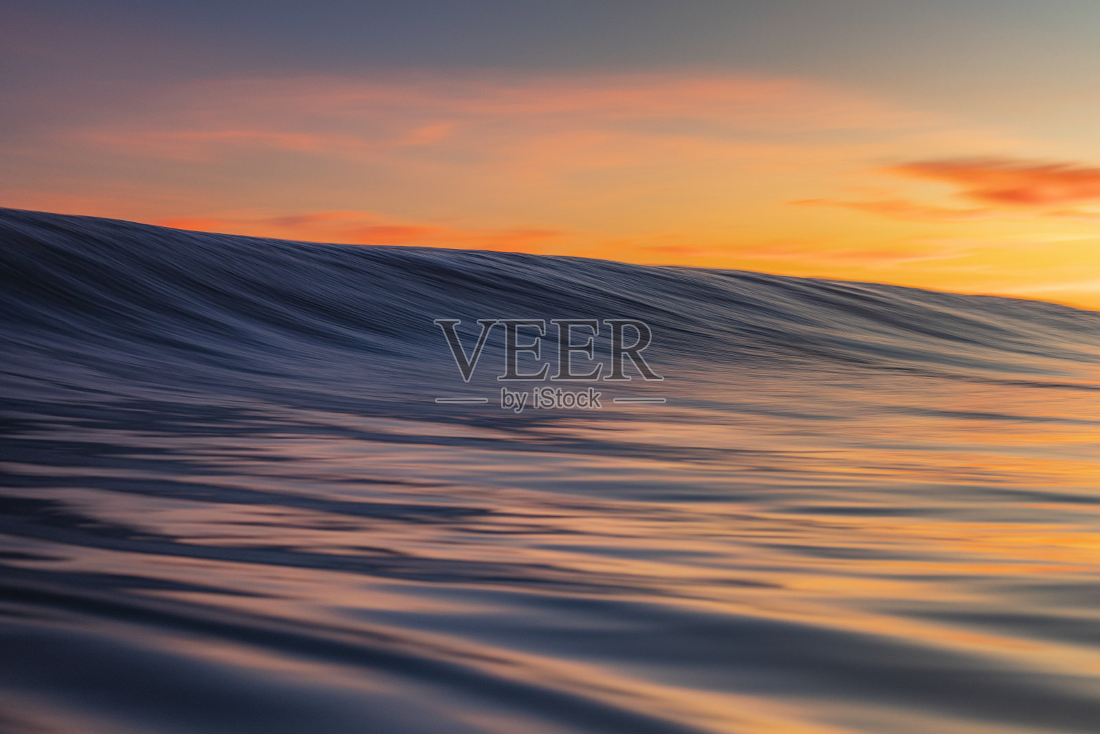 在温暖的日出海滩上形成平滑的波浪的特写照片摄影图片