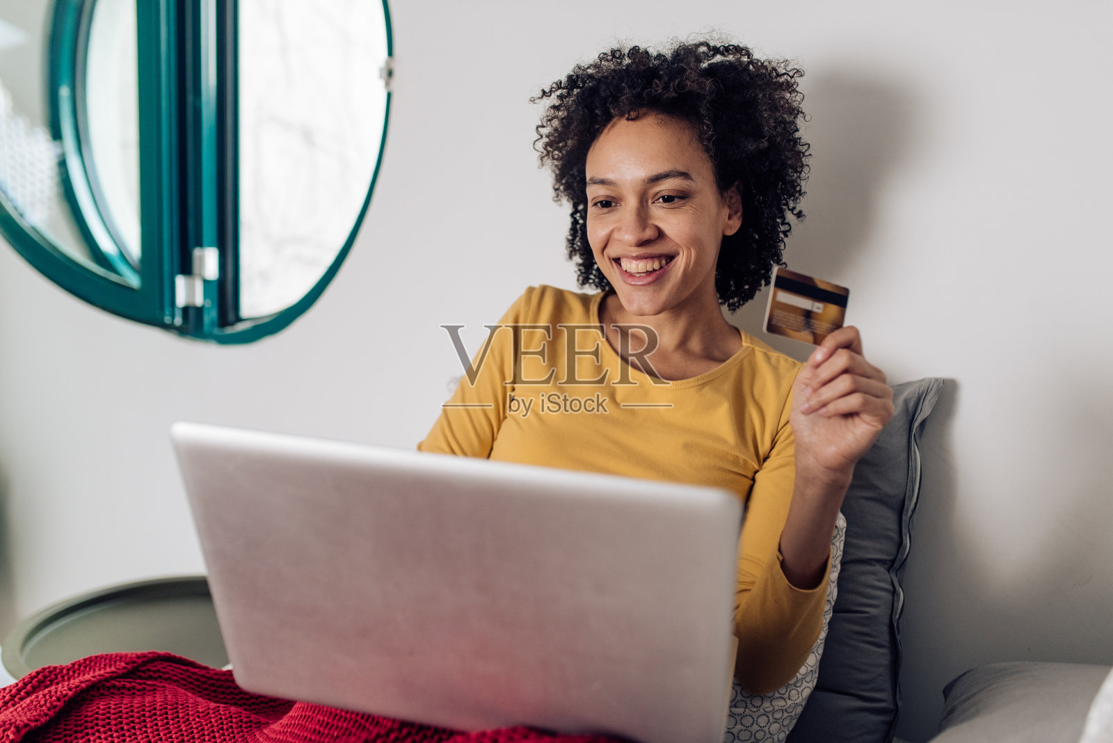 年轻的非洲女人享受在她的床上和网上购物照片摄影图片