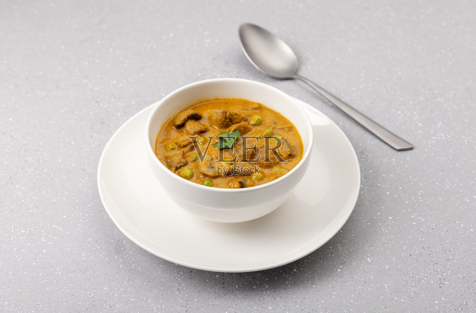 奶油豌豆和蘑菇咖喱放在一个白碗里照片摄影图片