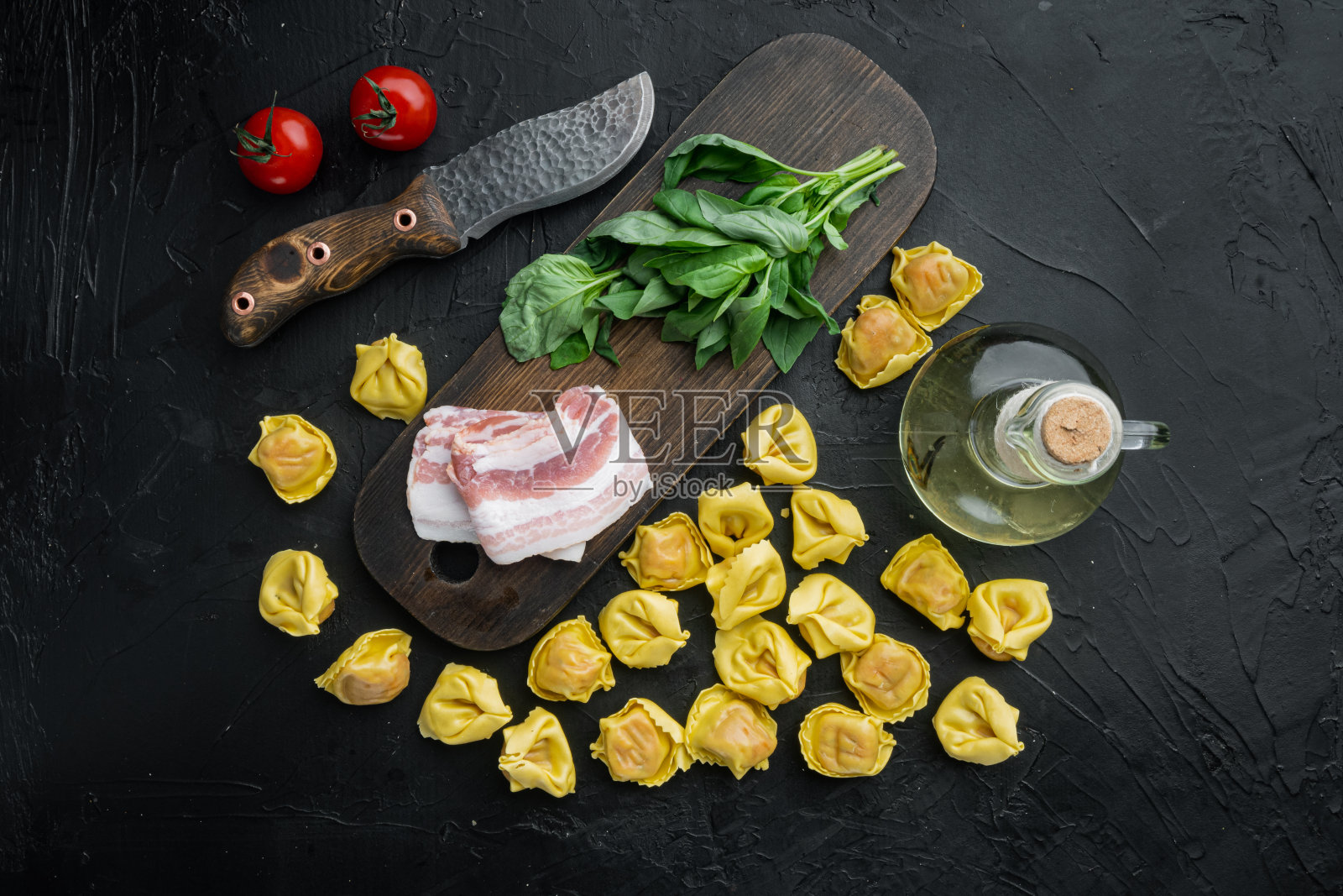 生的自制饺子与腌火腿,在木砧板上,在黑色的背景,俯视图平铺照片摄影图片