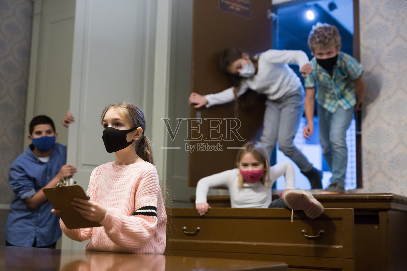 任务游戏- - -一群戴着防护面具的小朋友在寻找离开房间的路照片摄影图片