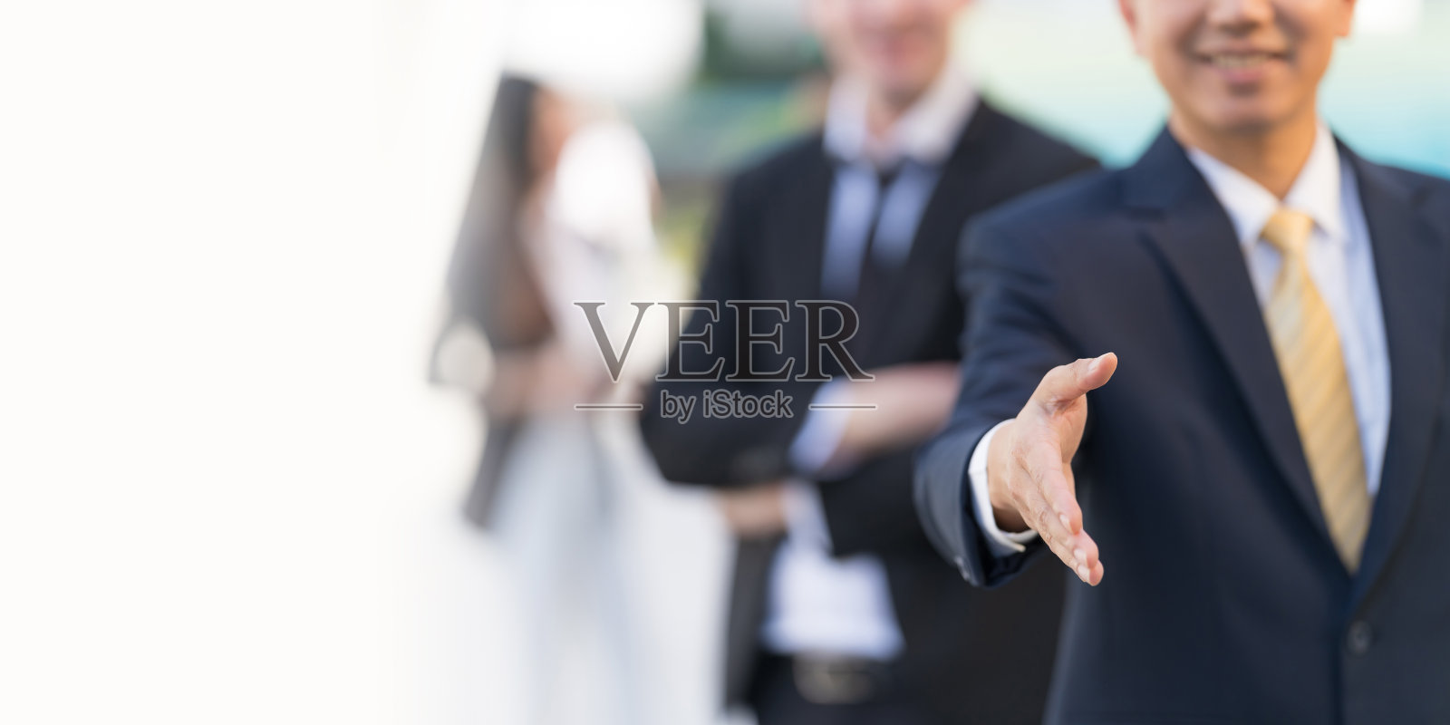 站在现代化的办公大楼前,商人张开手准备握手敲定交易照片摄影图片