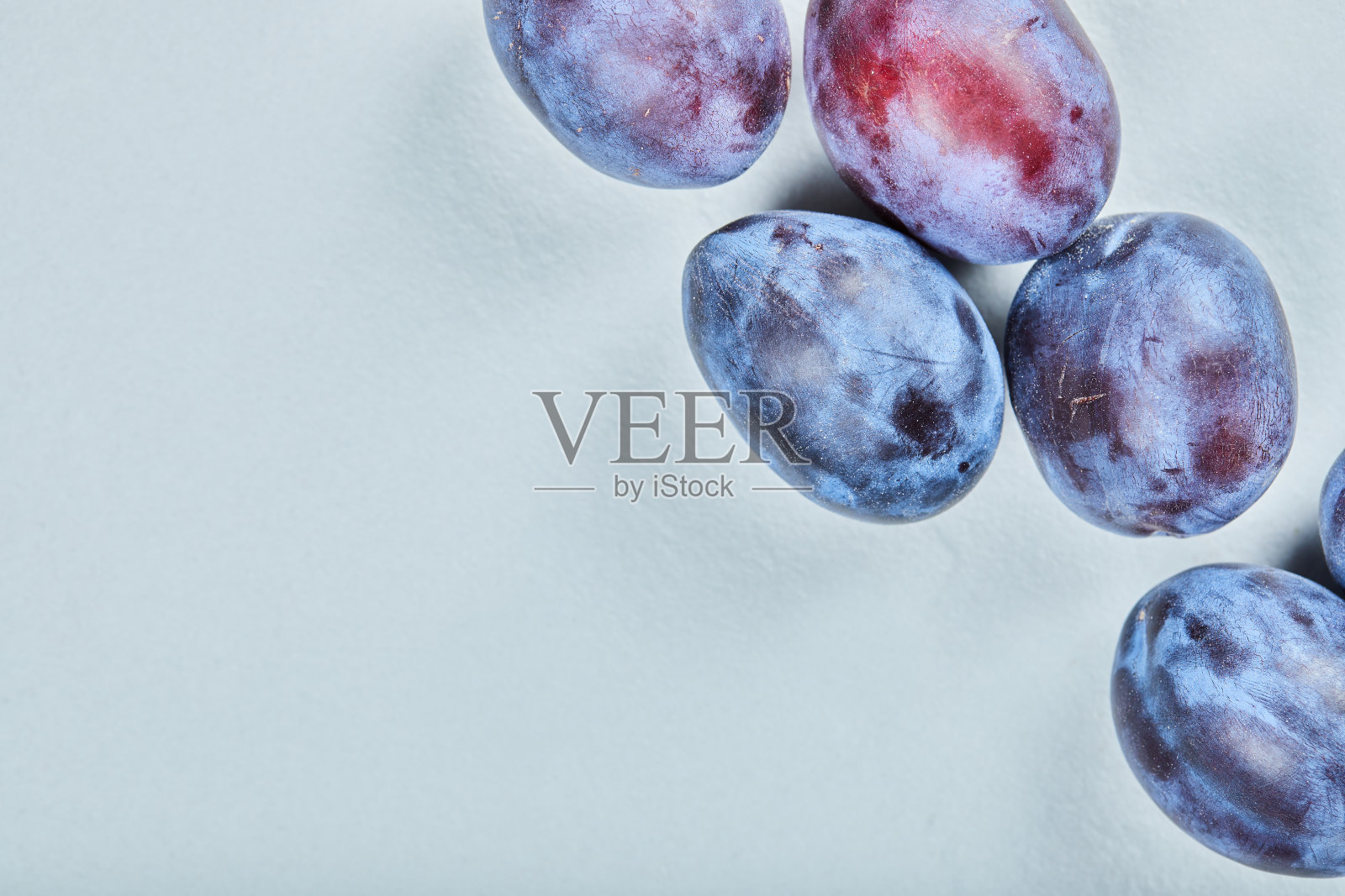 蓝色背景上的一组新鲜李子照片摄影图片