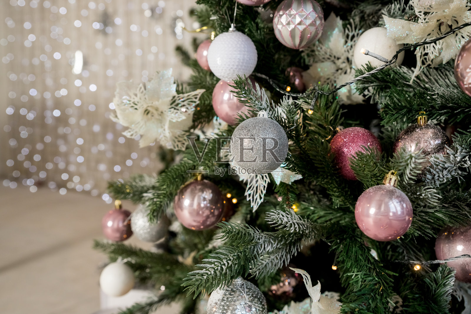 圣诞装饰圣诞树的闪光球特写。新年。温和柔和的颜色。时尚的装饰。白色、粉色和银色的装饰品。用彩灯、球和金属箔装饰的树枝。照片摄影图片