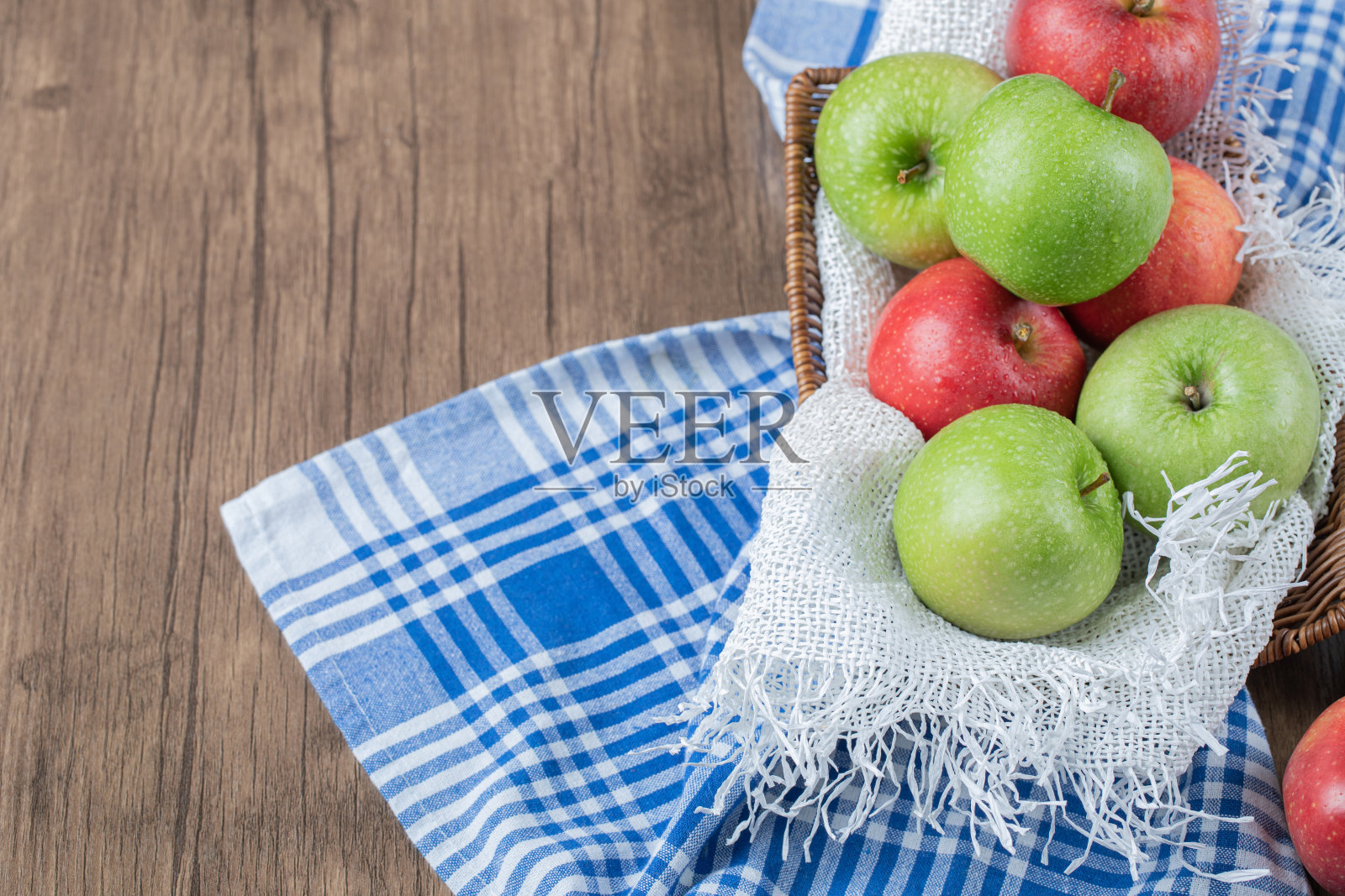 苹果放在篮子里,放在桌子上的白毛巾上照片摄影图片