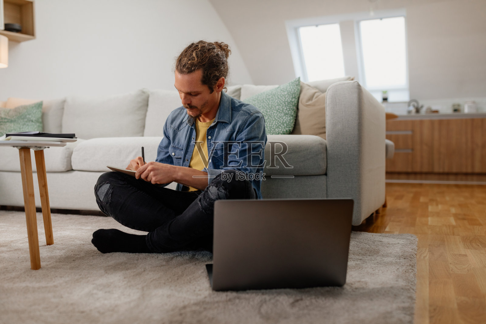年轻男性坐在地板上工作照片摄影图片